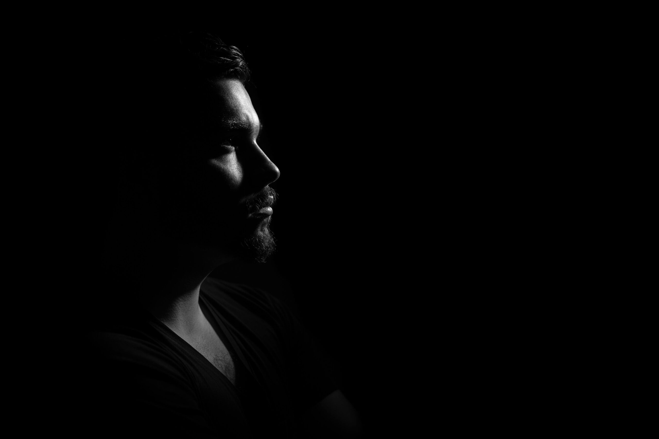 Profile portrait of a man in black and white, emphasizing shadows and highlights.